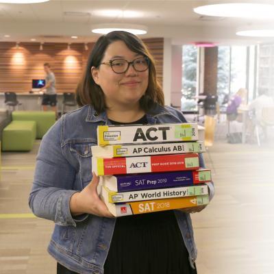 Photo os Tenn Services staff member holding large stack of test preparation materials